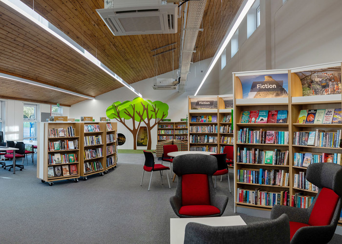 Library social space design — comfortable reading nook and seating area encouraging longer library visits