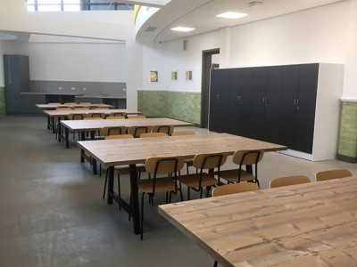 Long wooden tables with black metal legs and wooden chairs in a study area at Danum Library