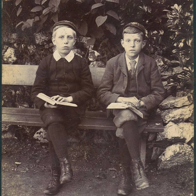 Two boys sat on bench reading