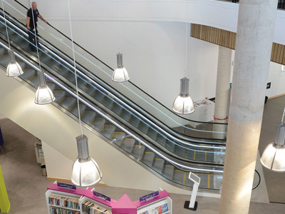 Escalators leading to upper levels beside a central book display unit at Southwater Library