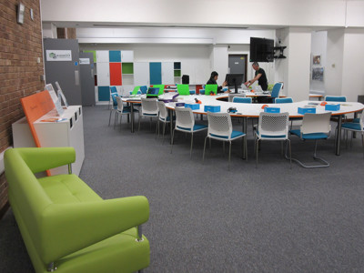 Bright green sofa and circular collaborative work tables in a makerspace at County Library Oxfordshire