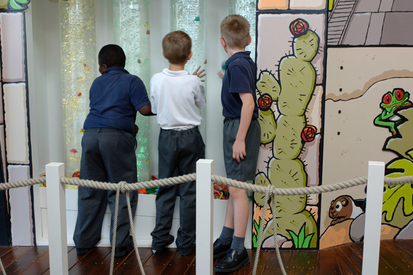 Three children observing a sensory water wall feature with colourful bubbles at Wentworth Primary School