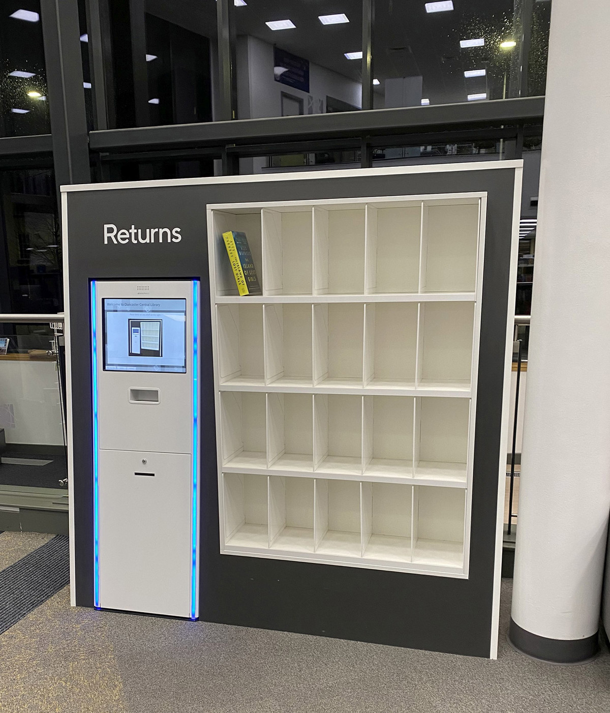 Self-service returns kiosk with a digital interface and empty shelving for book returns at Danum Library