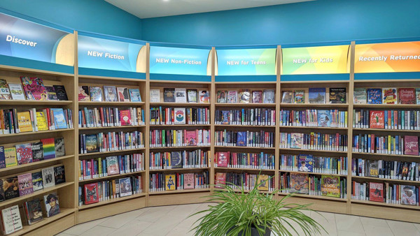 Curved wooden shelving displaying colourful book titles in a children's reading area at Painswick Branch