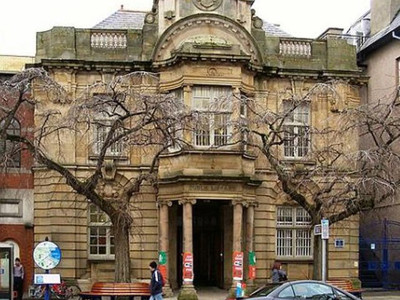 Historic stone façade with ornate architectural details and large windows at Llandudno Library
