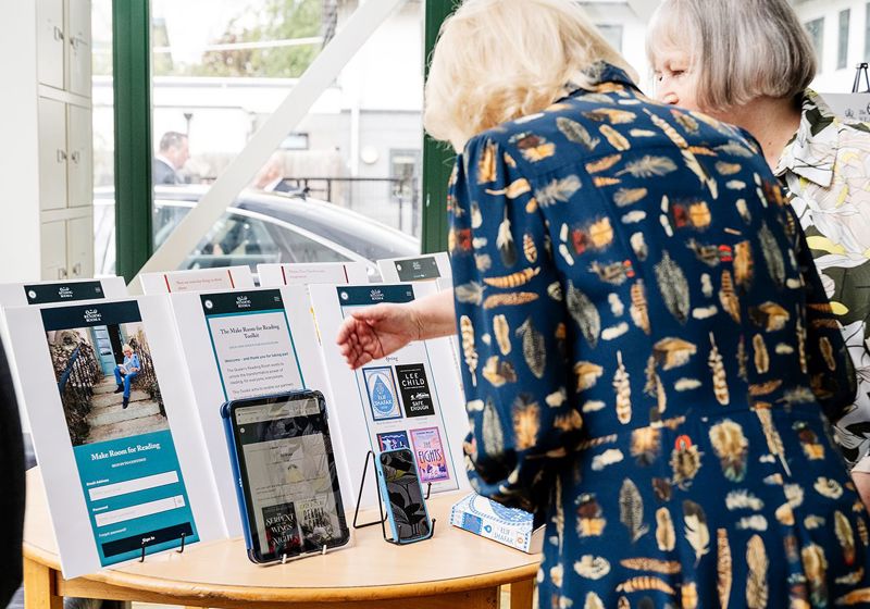 Rachel shows Her Majesty the Make Room for Reading Toolkit on tablet and phone