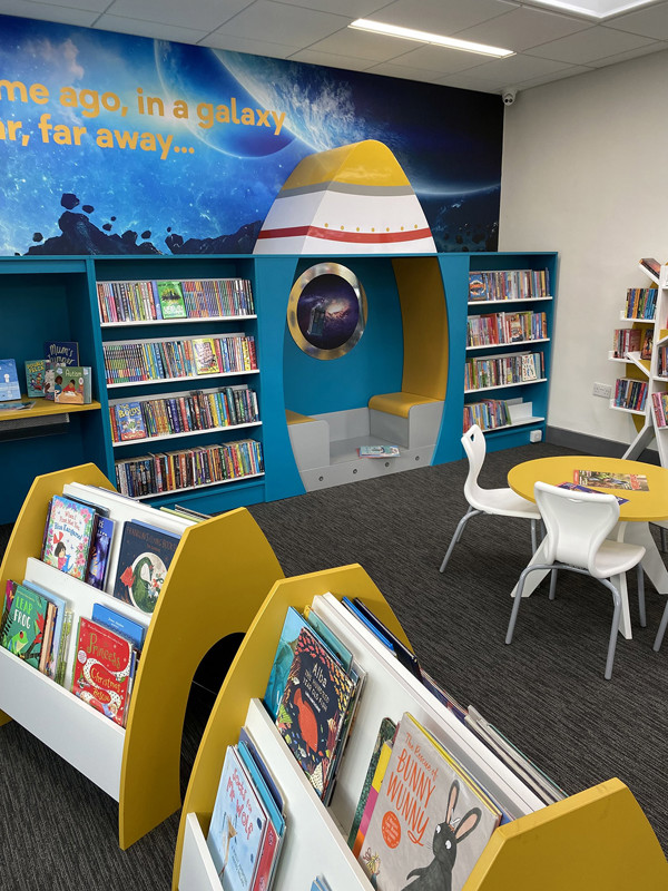 Bright yellow and blue spaceship-shaped book display with face-out titles in a children's reading area at Farsley Library