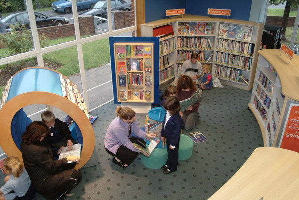 Children exploring books in a circular reading nook and browsing shelves at Ash Library