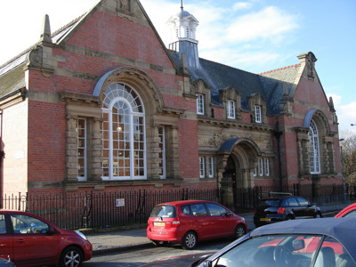 Red brick façade with large arched windows and a central entrance at Toxteth Library