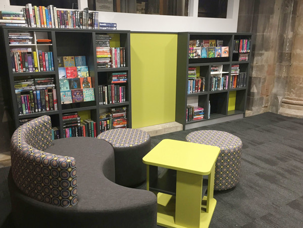 Circular grey seating with patterned upholstery and a lime green table beside colourful book displays at Lichfield Library