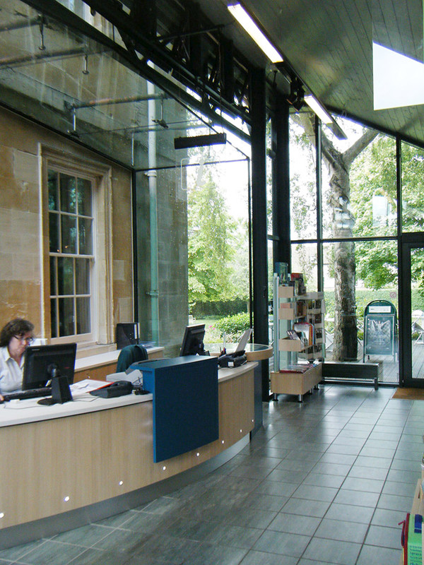 Curved wooden help desk with computer stations and large windows overlooking greenery at Woodstock Museum Library