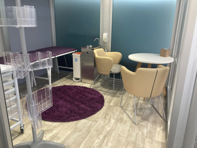 Round white table and upholstered chairs on a purple rug in a quiet reading space at Leeds Wellbeing Pods