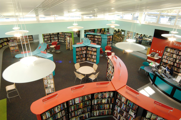 Curved orange shelving units and turquoise browsing areas create an engaging layout for book discovery at Yate Library