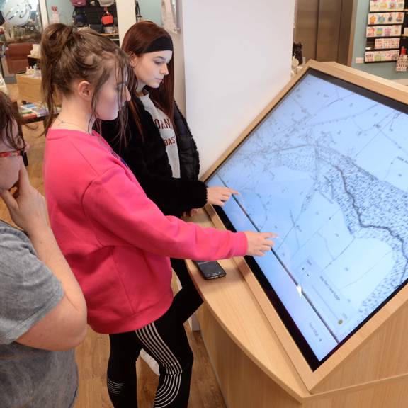 Teenagers using touch screen to showcase digital maps