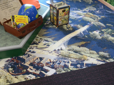 Colourful carpet featuring a detailed aerial view of a bridge and surrounding landscape in a children's reading area at Southwater Library