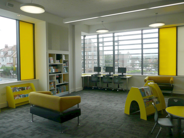 Yellow upholstered sofa and browsing shelves in a children's reading area at Seaford Library