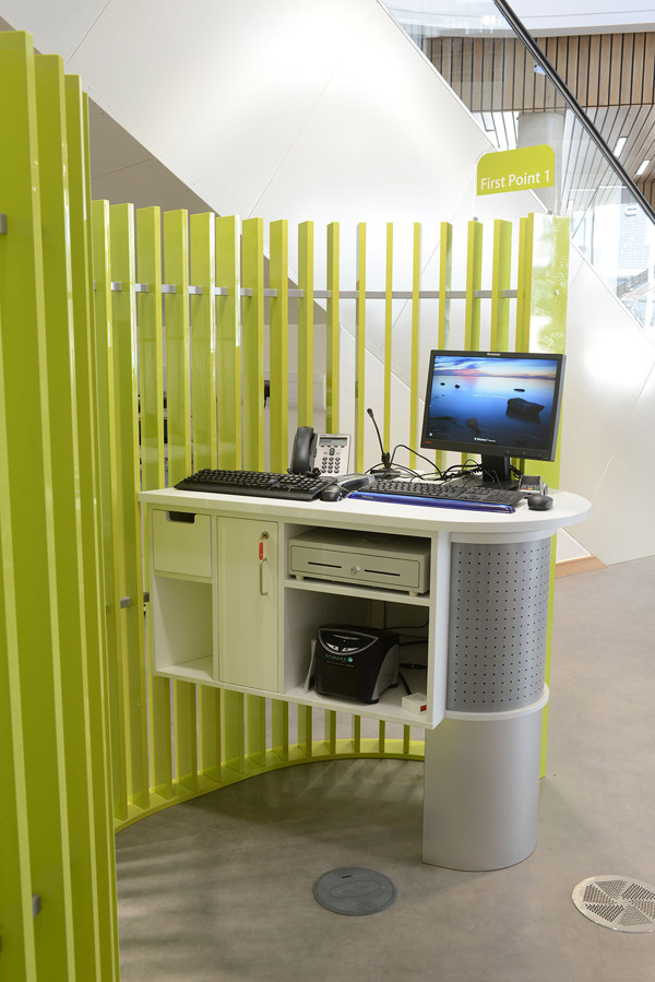 Curved service desk with a computer and phone, surrounded by green slatted partitions at Southwater Customer Services