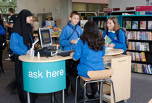 Library help desk design — modern welcome counter and staff pod in a public library interior
