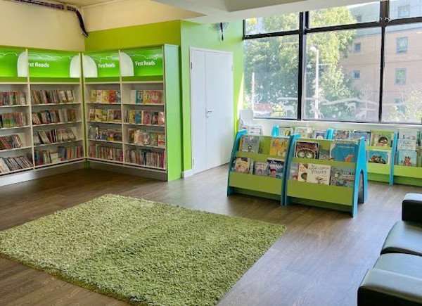 Bright green walls and a plush rug complement face-out book displays in a children's reading area at South Woodford Library