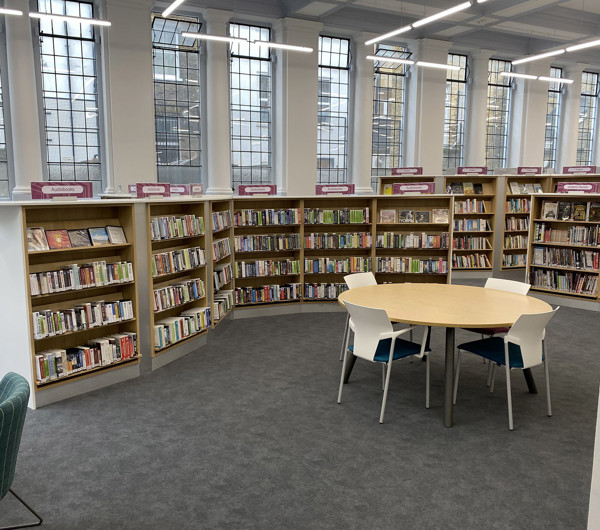 Curved shelving filled with books surrounding a circular study table and chairs in a browsing space at Islington Central Library