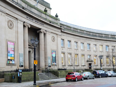 Curved stone façade and large windows of the historic Bolton Library building, showcasing its architectural features at Bolton Library