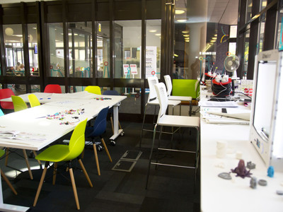 Brightly coloured chairs around collaborative work tables in a makerspace at Redbridge Lab Central