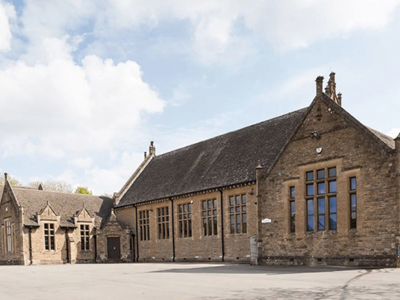 Stone architecture with large windows and a slate roof at Kingham Hill School, showcasing heritage design elements