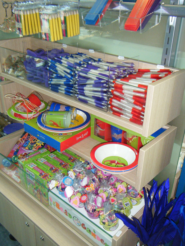 Colourful stationery items and toys arranged in clear display boxes at Woodstock Museum Shop – product display detail