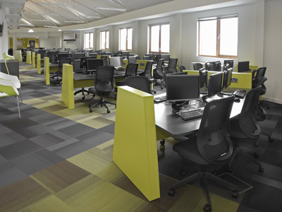 Bright green workstations with black chairs and computers in a study area at Boots Library