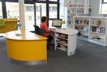 Library help desk design — modern welcome counter and staff pod in a public library interior