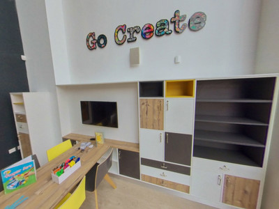 Bright yellow chairs and a wooden table in a creative space with storage units at Danum Library