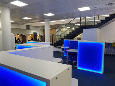 Illuminated white work pods with blue backlighting in a collaborative workspace at Shoreditch Library