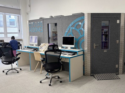 Black office chairs and a grey acoustic pod with blue accents in a digital collaboration space at Leeds Music Library