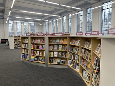 Curved wooden browsing shelves filled with books in a spacious reading area at Islington Central Library