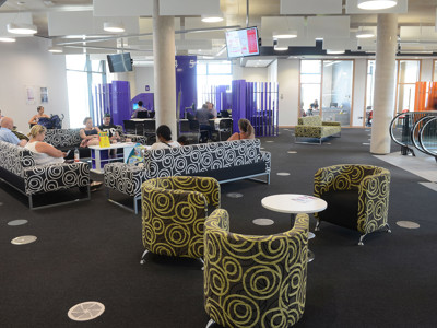 Circular patterned lounge chairs and patterned sofas in a public library seating area at Southwater Library