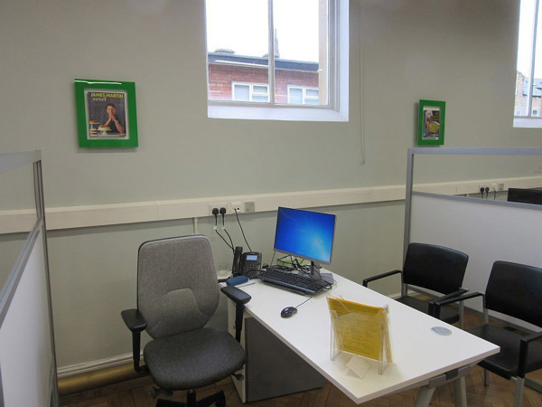 Grey office chair and a white desk with a computer in an advice desk area at Morley Library