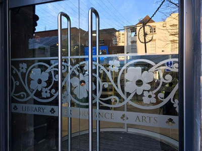 Decorative glass doors featuring floral patterns and text at the entrance to Lichfield Library