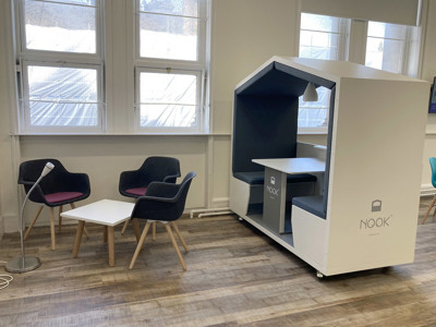 Stylish nook pod with a desk and two upholstered chairs beside a side table in a collaborative work area at BIPC Leeds