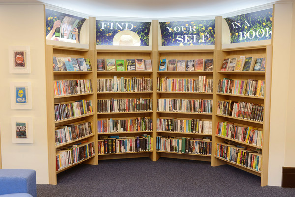 Curved wooden shelving displaying a diverse range of books in a browsing space at Kingham Hill School