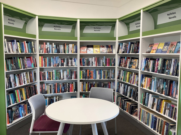 Curved white shelving filled with novels in a dedicated reading corner at Uwchaled Library