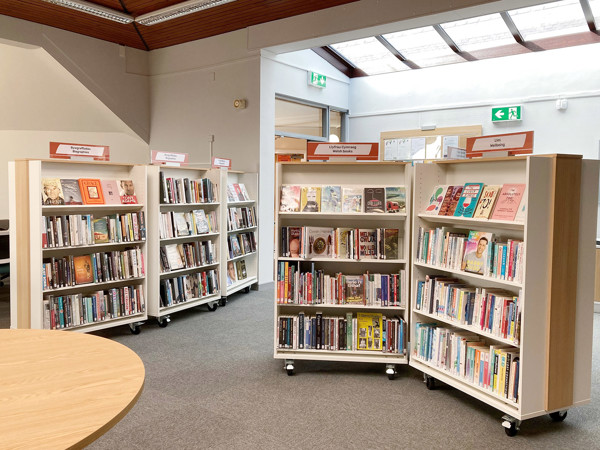Mobile browser shelving units filled with books in a public library browsing area at Kinmel Bay Library