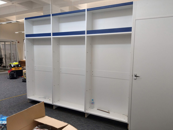 Custom shelving units with blue accents and adjustable shelves in a library installation area at Hunslet Library