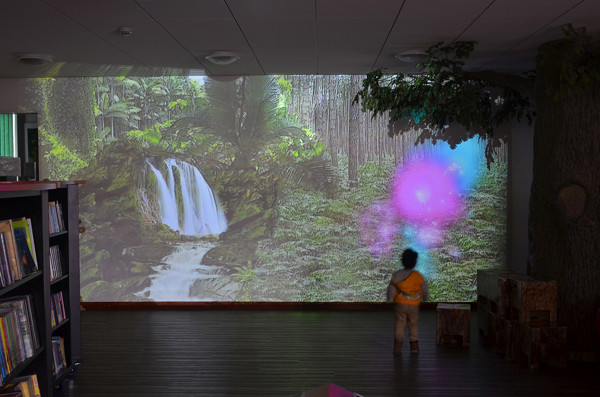 A child interacting with a projected nature scene featuring a waterfall and vibrant colours at Redbridge Central Library