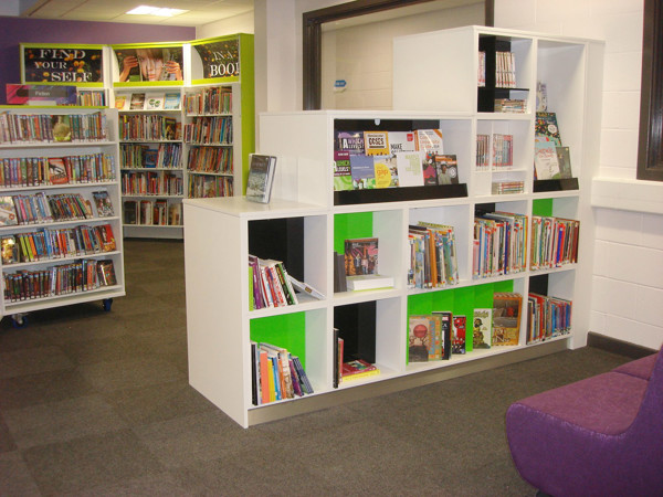 White shelving unit with green back panels displaying books and magazines in a young readers' browsing space at Werneth School Library