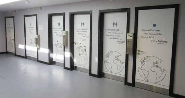 Decorative doors with illustrations and quotes about libraries in a corridor at Wrexham Library