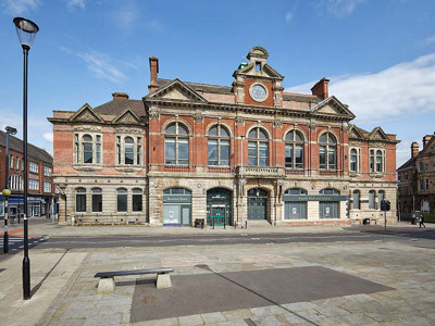 Grand red brick façade with arched windows and decorative stonework at Tunstall Library