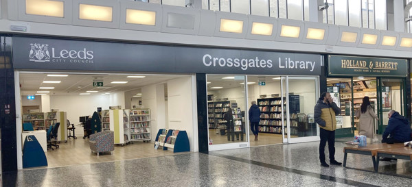 Brightly lit entrance with large glass windows showcasing browsing shelves and seating areas at Crossgates Library