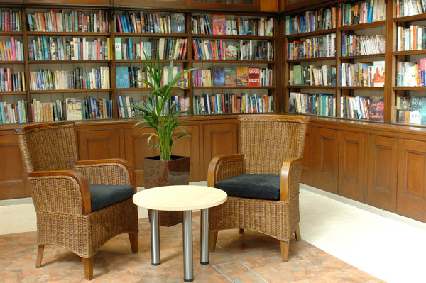 Wicker armchairs and a small table beside a plant in a quiet reading space at Wimbledon Library