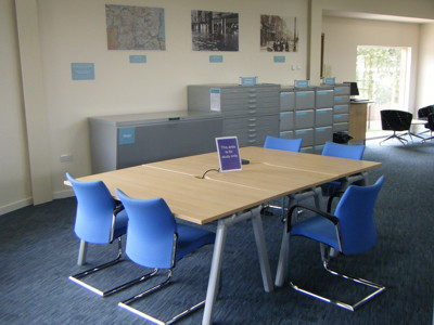 Light blue study chairs around a wooden study table in a quiet reading space at Worksop Local Studies