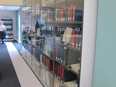 Glass display cabinets showcasing neatly arranged local history books and archival materials in a special collections area at West Bridgford Local Studies